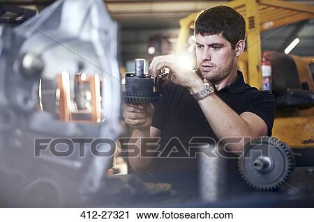 Mechanic examining part in auto repair shop View Large Photo Image Stock Image - Mechanic examining part in auto repair shop. Fotosearch