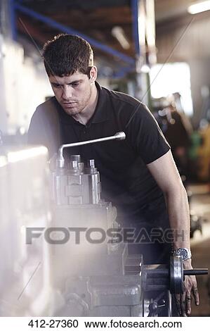 Mechanic working at machinery in auto repair shop View Large Photo Image Stock Image - Mechanic working at machinery in auto repair shop. Fotosearch