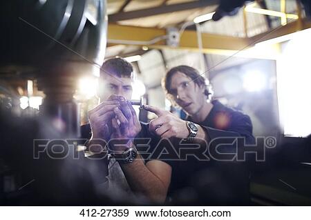 Mechanics examining part in auto repair shop View Large Photo Image Stock Photo - Mechanics examining part in auto repair shop. Fotosearch
