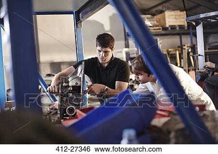 Mechanics examining part in auto repair shop View Large Photo Image Stock Photograph - Mechanics examining part in auto repair shop. Fotosearch
