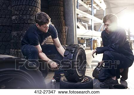 Stock Photo - Mechanics fixing tire in auto repair shop. Fotosearch