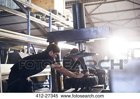 Stock Photography - Mechanics fixing tire in auto repair shop. Fotosearch
