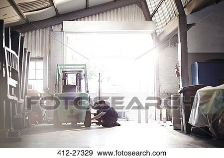Mechanics repairing forklift in auto repair shop View Large Photo Image Stock Photo - Mechanics repairing forklift in auto repair shop. Fotosearch