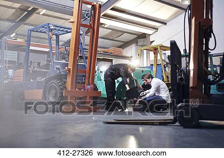 Mechanics working near forklift in auto repair shop View Large Photo Image Stock Photograph - Mechanics working near forklift in auto repair shop. Fotosearch