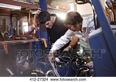 Mechanics working on car in auto repair shop View Large Photo Image Picture - Mechanics working on car in auto repair shop. Fotosearch