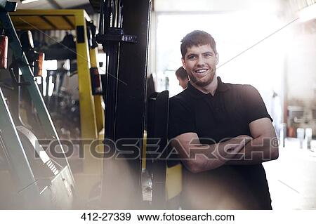 Portrait confident mechanic leaning on forklift in auto repair shop View Large Photo Image Stock Photo - Portrait confident mechanic leaning on forklift in auto repair shop. Fotosearch