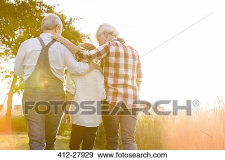 Affectionate grandparents and grandson walking along sunny rural wheat field View Large Photo Image Stock Photo - Affectionate grandparents and grandson walking along sunny rural wheat field. Fotosearch