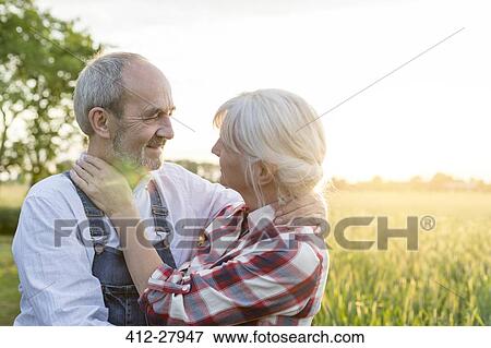 Affectionate senior couple hugging in sunny rural wheat field View Large Photo Image Stock Photo - Affectionate senior couple hugging in sunny rural wheat field. Fotosearch
