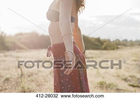 Boho woman in bikini top and skirt with arms outstretched in sunny rural field View Large Photo Image Stock Image - Boho woman in bikini top and skirt with arms outstretched in sunny rural field. Fotosearch