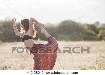 Boho woman in king dancer yoga pose in sunny rural field View Large Photo Image Stock Image - Boho woman in king dancer yoga pose in sunny rural field. Fotosearch