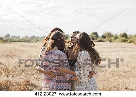 Stock Photo - Boho women hugging in rural field. Fotosearch