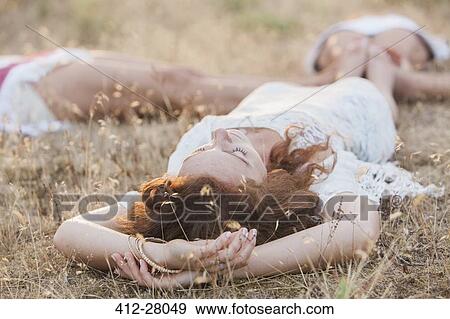Boho women laying in circle with feet touching in rural field View Large Photo Image Stock Photo - Boho women laying in circle with feet touching in rural field. Fotosearch
