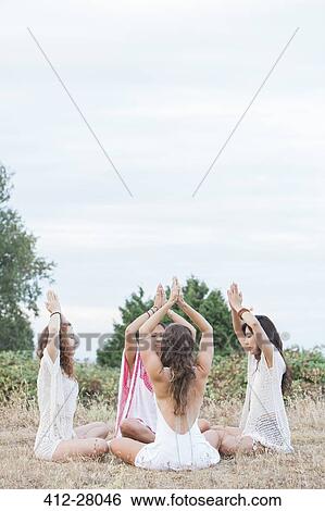 Boho women meditating with hands clasped overhead in circle in rural field View Large Photo Image Stock Photograph - Boho women meditating with hands clasped overhead in circle in rural field. Fotosearch