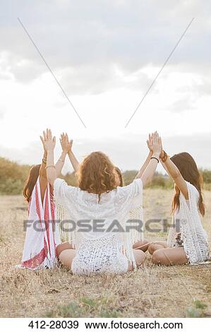 Boho women sitting in circle with arms raised and connected in rural field View Large Photo Image Stock Photo - Boho women sitting in circle with arms raised and connected in rural field. Fotosearch
