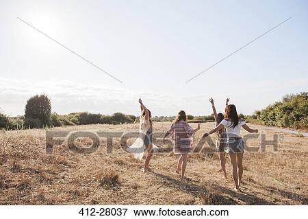 Carefree boho women dancing in sunny rural field View Large Photo Image Stock Photo - Carefree boho women dancing in sunny rural field. Fotosearch