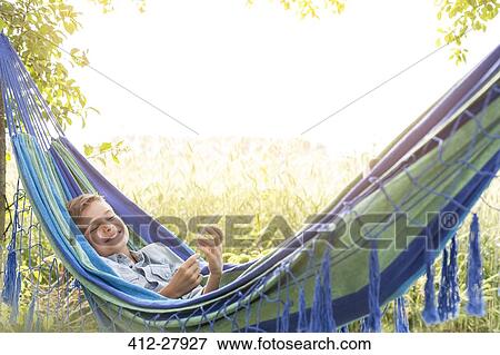 Carefree boy listening to music on mp3 player in rural hammock View Large Photo Image Stock Photo - Carefree boy listening to music on mp3 player in rural hammock. Fotosearch