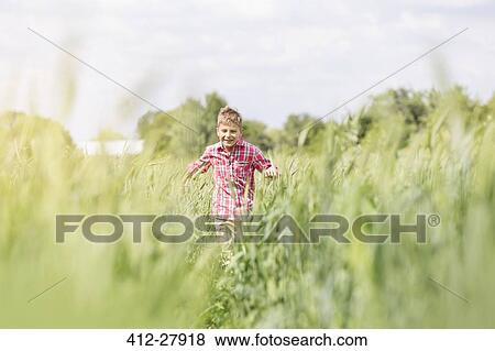 Stock Photo - Carefree boy running in sunny rural field. Fotosearch
