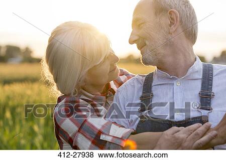 Stock Photo - Close up affectionate senior couple hugging in rural field. Fotosearch