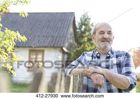 Confident farmer leaning on fence outside farmhouse View Large Photo Image Stock Image - Confident farmer leaning on fence outside farmhouse. Fotosearch