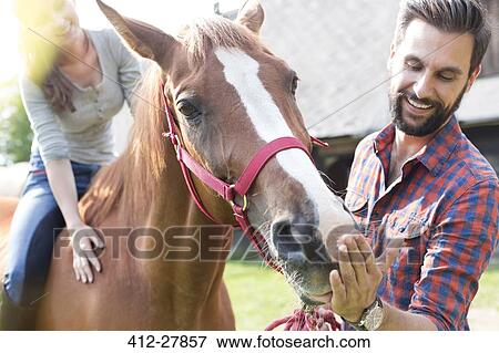 Couple feeding horse View Large Photo Image Stock Photo - Couple feeding horse. Fotosearch