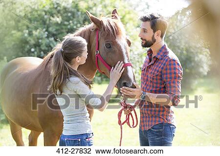 Couple petting horse View Large Photo Image Stock Image - Couple petting horse. Fotosearch