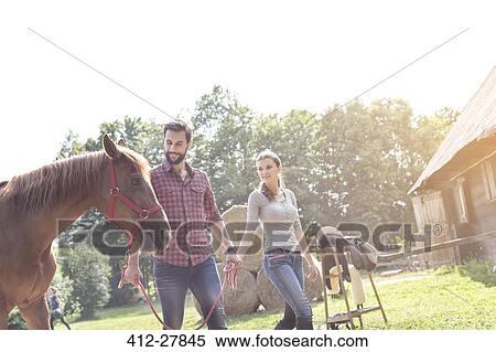 Couple walking horse outside rural barn View Large Photo Image Stock Photography - Couple walking horse outside rural barn. Fotosearch