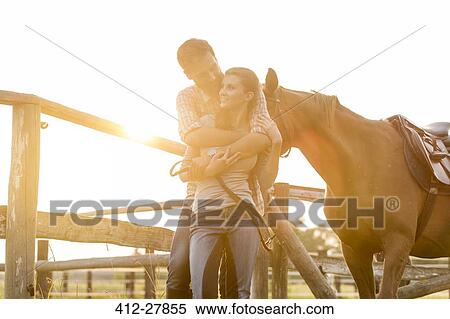 Couple with horse hugging in sunny rural pasture View Large Photo Image Stock Photography - Couple with horse hugging in sunny rural pasture. Fotosearch