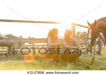 Stock Photo - Couple with horse talking in sunny rural pasture. Fotosearch
