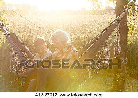 Grandmother and grandson reading book in sunny rural hammock View Large Photo Image Stock Image - Grandmother and grandson reading book in sunny rural hammock. Fotosearch