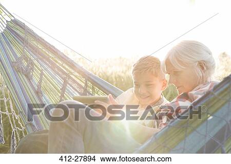 Grandmother and grandson using digital tablet in sunny hammock View Large Photo Image Picture - Grandmother and grandson using digital tablet in sunny hammock. Fotosearch