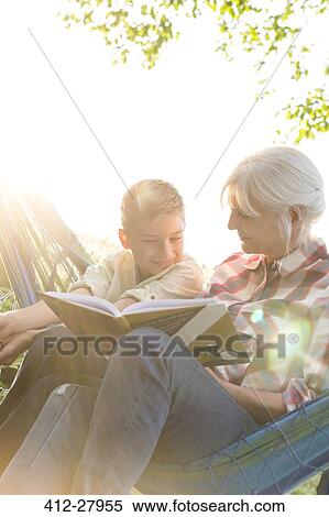 Stock Photography - Grandmother reading to grandson in sunny hammock. Fotosearch