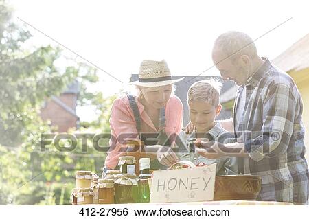 Grandparents and grandson selling honey at farmer’s market stall View Large Photo Image Stock Photograph - Grandparents and grandson selling honey at farmer’s market stall. Fotosearch