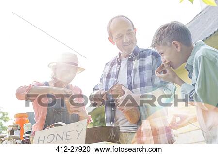 Grandparents and grandson tasting and selling honey at farmer’s market View Large Photo Image Stock Image - Grandparents and grandson tasting and selling honey at farmer’s market. Fotosearch