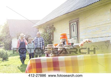Stock Photograph - Grandparents and grandson walking toward rural honey stand. Fotosearch