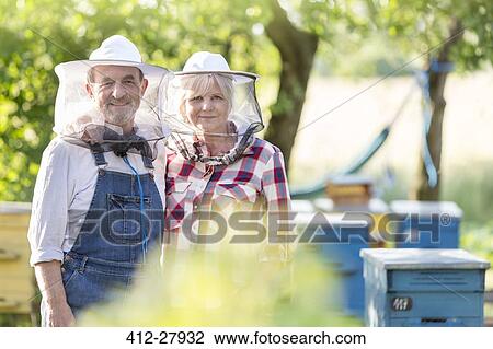 Portrait confident beekeepers in protective hats near hives View Large Photo Image Stock Image - Portrait confident beekeepers in protective hats near hives. Fotosearch