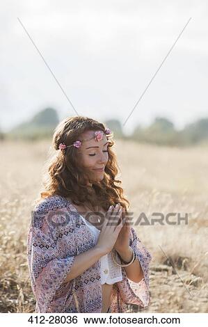 Serene boho woman meditating with hands at heart center in sunny rural field View Large Photo Image Stock Photograph - Serene boho woman meditating with hands at heart center in sunny rural field. Fotosearch