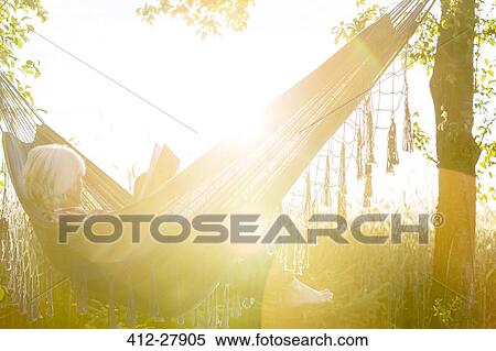 Serene woman reading book in sunny hammock View Large Photo Image Stock Photography - Serene woman reading book in sunny hammock. Fotosearch