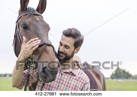 Stock Image - Smiling man hugging horse. Fotosearch