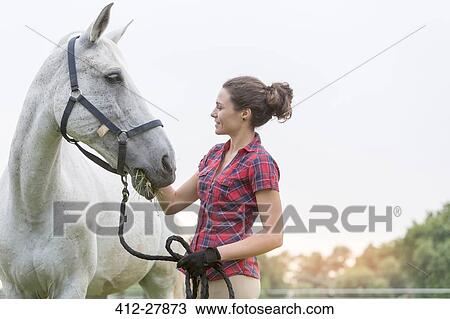 Woman feeding horse View Large Photo Image Stock Image - Woman feeding horse. Fotosearch