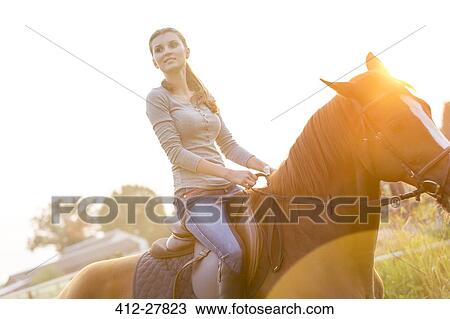Stock Image - Woman horseback riding. Fotosearch