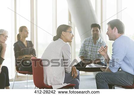 Stock Image - Business people discussing paperwork in meeting. Fotosearch