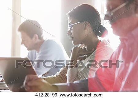 Businesswoman working at laptop in meeting View Large Photo Image Stock Photo - Businesswoman working at laptop in meeting. Fotosearch
