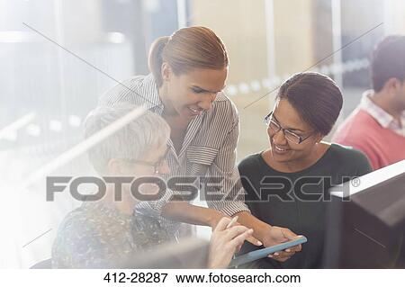 Stock Photo - Businesswomen with digital tablet at computers in office. Fotosearch