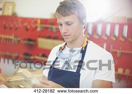 Carpenter examining wood in workshop View Large Photo Image Stock Image - Carpenter examining wood in workshop. Fotosearch