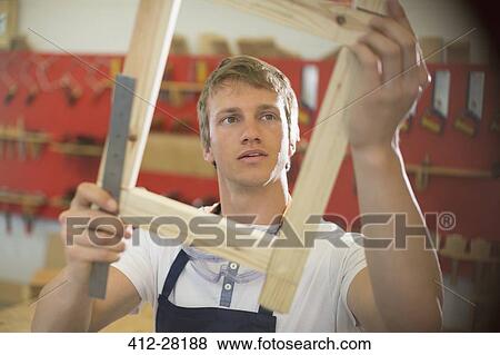 Stock Photo - Carpenter examining wood in workshop. Fotosearch
