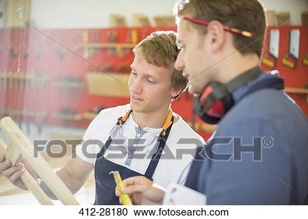 Stock Image - Carpenters examining wood in workshop. Fotosearch