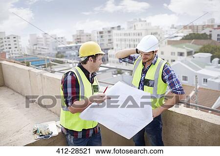 Construction worker and engineer reviewing blueprints at highrise construction site View Large Photo Image Stock Image - Construction worker and engineer reviewing blueprints at highrise construction site. Fotosearch