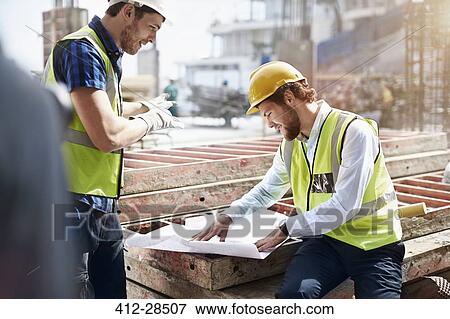 Construction worker and engineer reviewing blueprints at construction site View Large Photo Image Stock Photo - Construction worker and engineer reviewing blueprints at construction site. Fotosearch