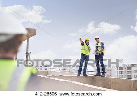 Stock Photograph - Construction worker and engineer talking at highrise construction site. Fotosearch