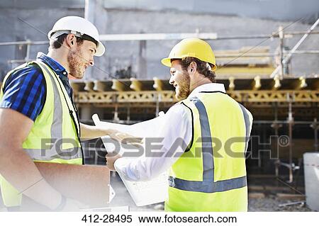 Stock Photography - Construction worker and engineer reviewing blueprints at construction site. Fotosearch